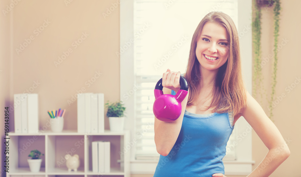 Happy young woman working out with a kettlebell