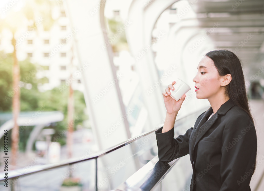 年轻的亚洲女性站在街道模糊的建筑背景下。bea的时尚商务照片