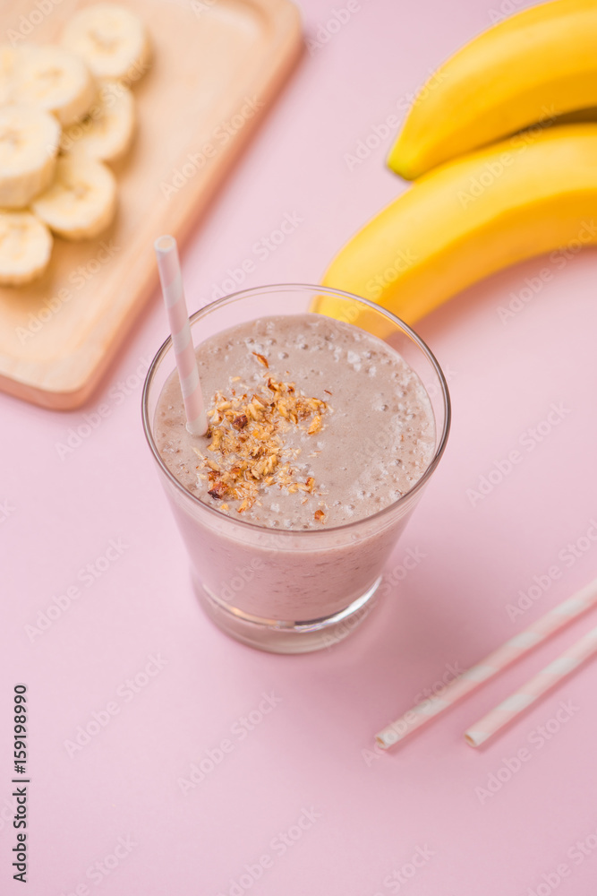 Fresh made banana smoothie in a glass on pink background