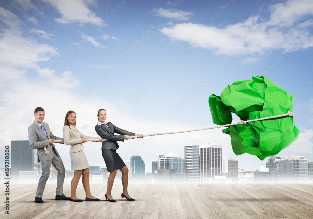 Young business people outdoors and huge paper ball as symbol of creativity