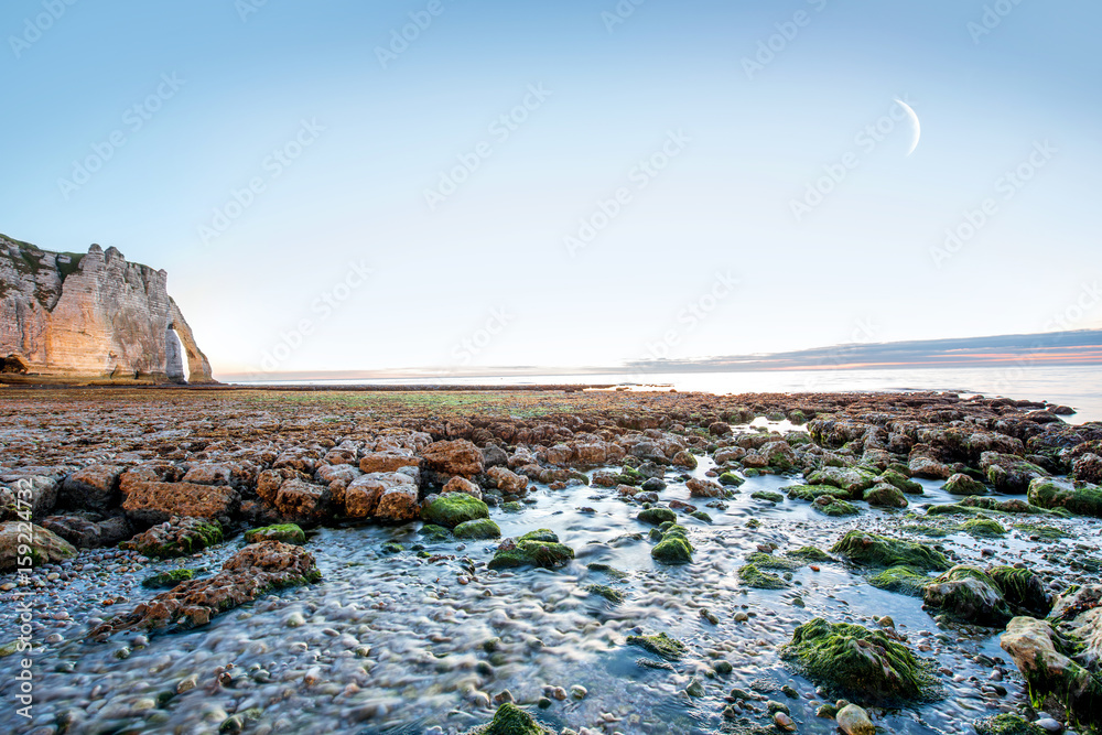 Twilight landscape view on the rocky coastline near Etretat town during the water ebb in France