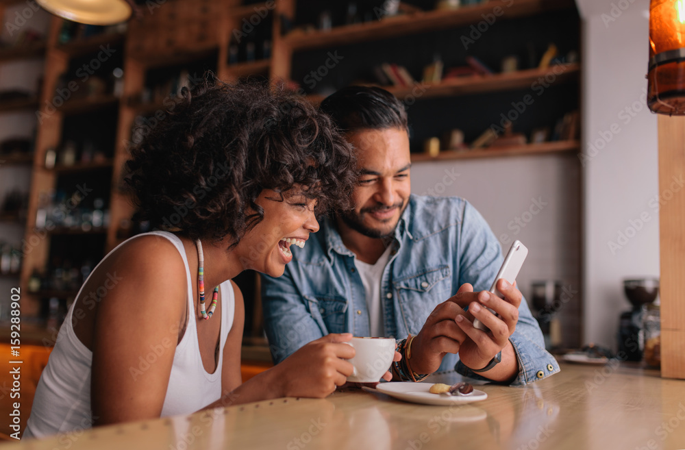 Happy couple at cafe using smart phone