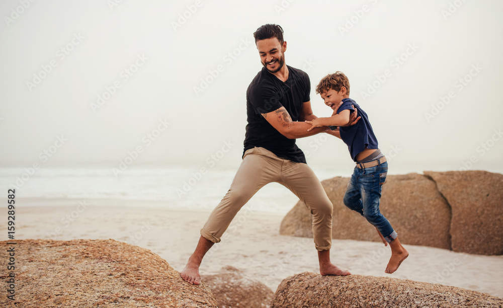 Father and son playing on the rocky sea shore