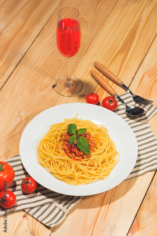 Plate of tasty spaghetti with tomato sauce and meat on wooden table.