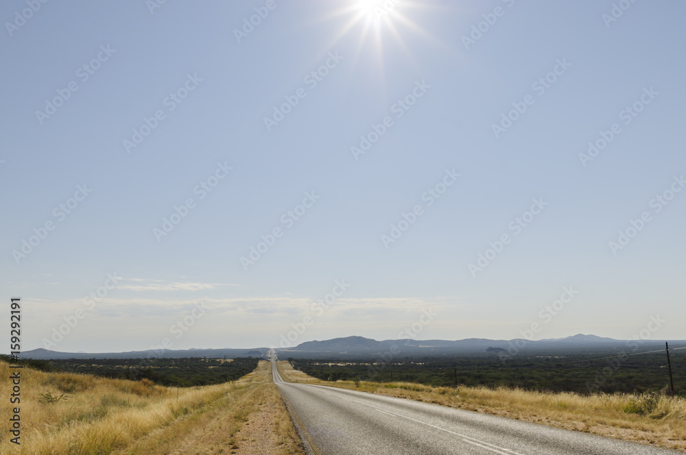 Strasse and Sonne的gerader Landschaft mit Strasse bis zum Horizont and Sonne