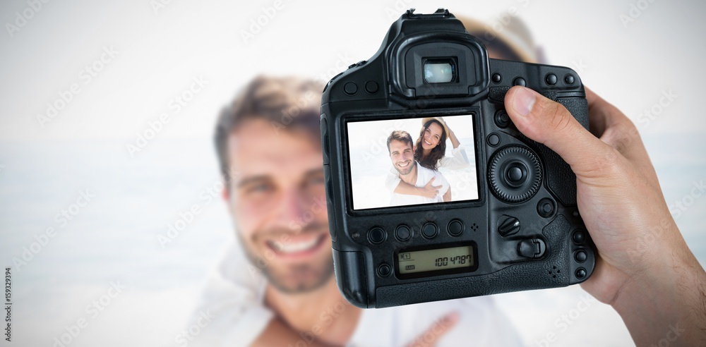 Composite image of cropped hand of photographer holding camera 