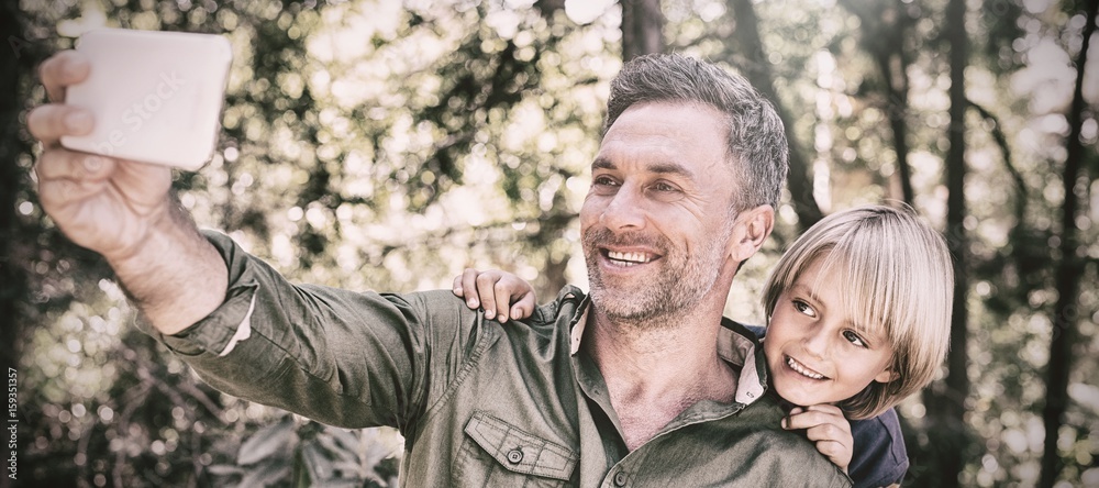 Smiling father and son taking selfie in forest