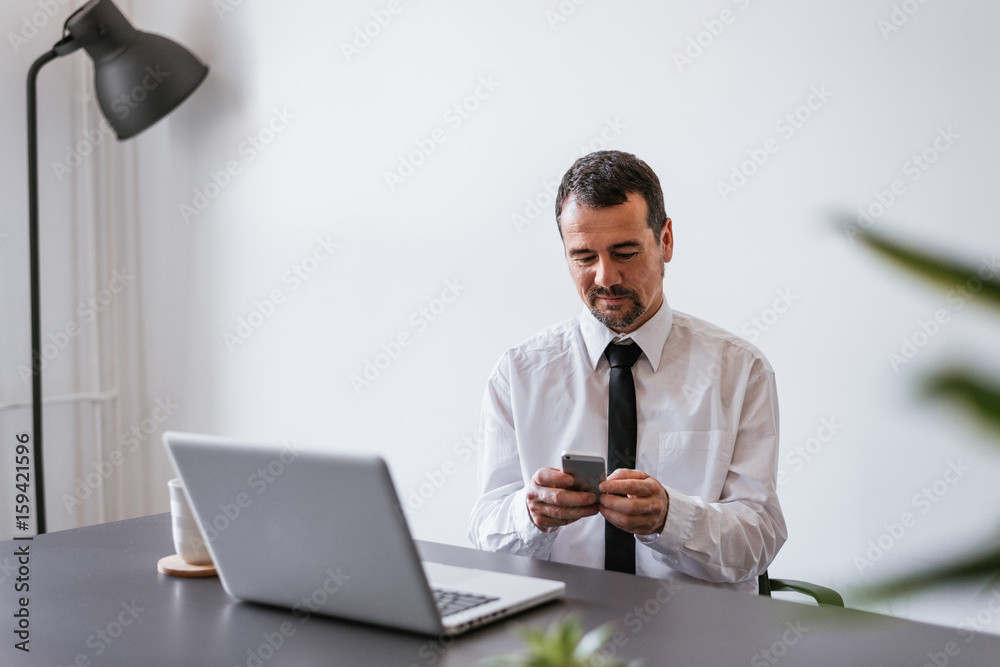 Mature man using mobile phone and laptop