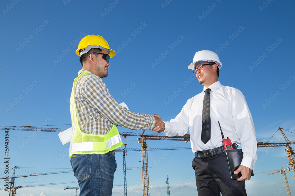 Construction engineer with worker shaking hands at construction site