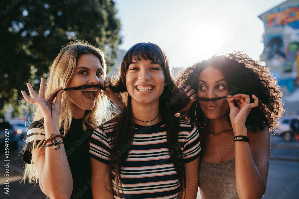 Girls in city pretending to have mustaches