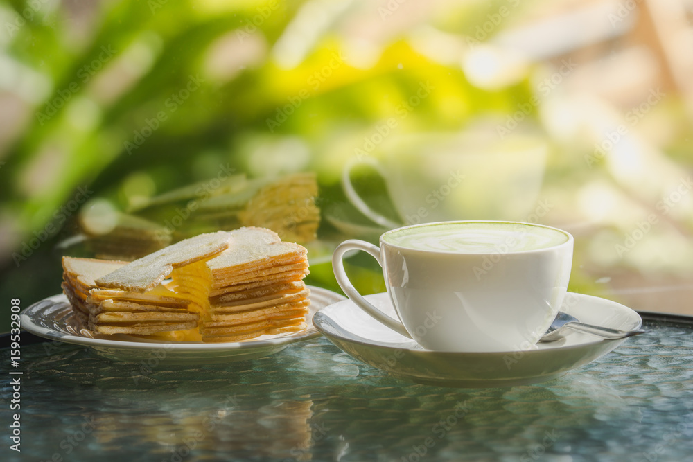 Hot green tea with biscuits on the table and a reflection mirror.