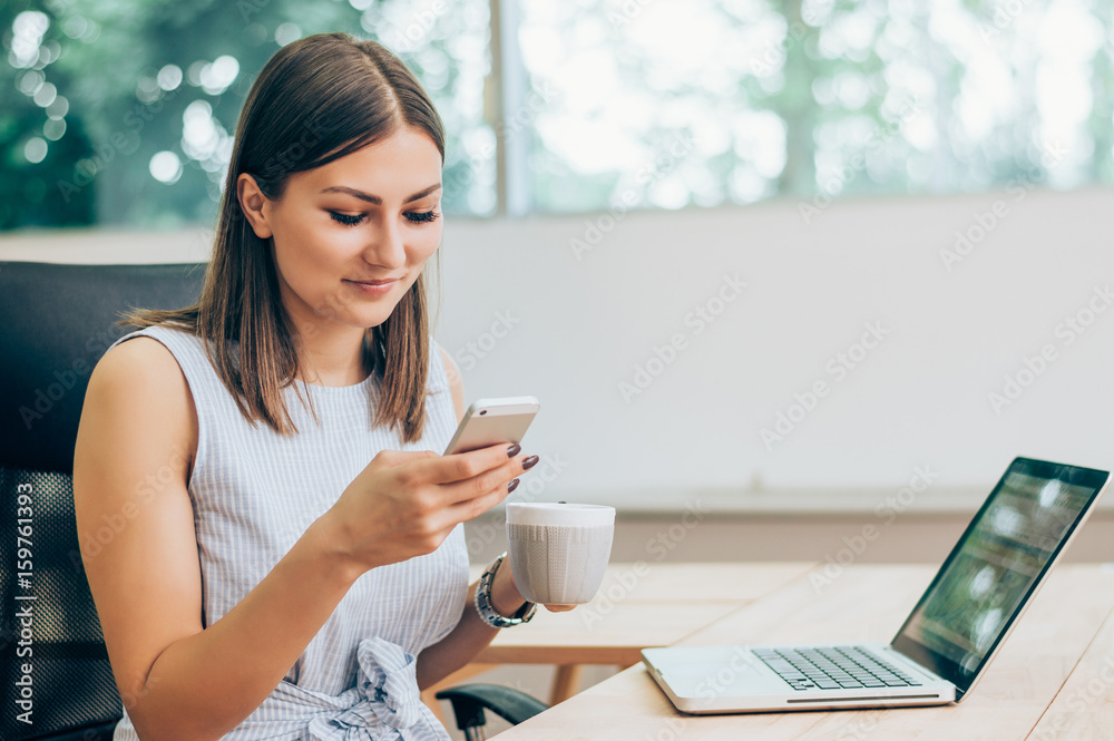 Portrait of smiling modern business woman in office using her mobile phone.