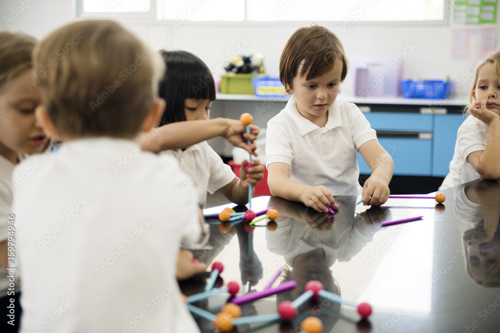 Diverse kindergarten students holding learning structures from toys