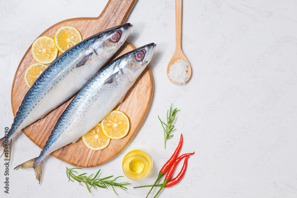 Fish dish cooking with various ingredients. Fresh raw fish decorated with lemon slices and herbs on 