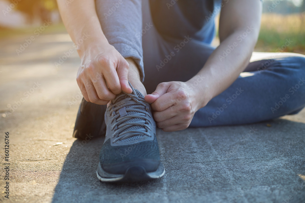 Young Asian man putting on pair of shoes, Tie the laces on the shoes