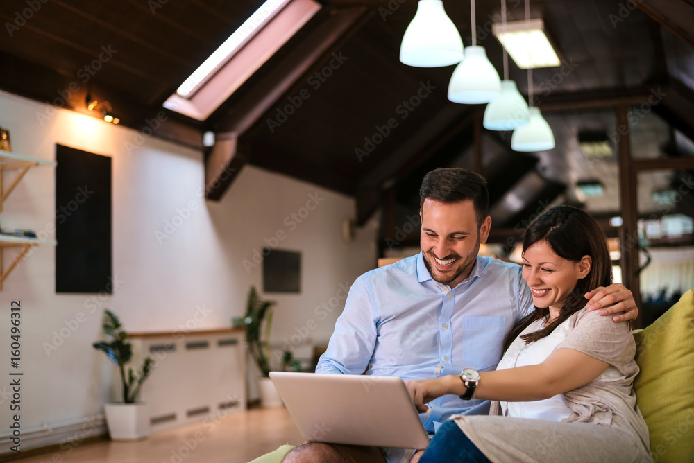 Happy couple with laptop spending time together at home