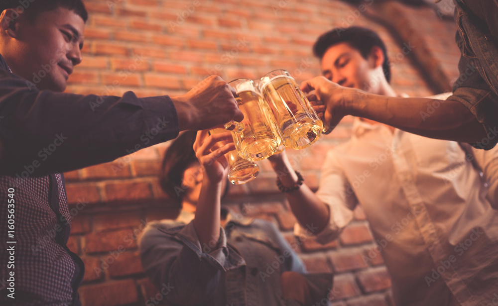 亚洲人正在庆祝节日，他们碰杯啤酒，晚餐快乐