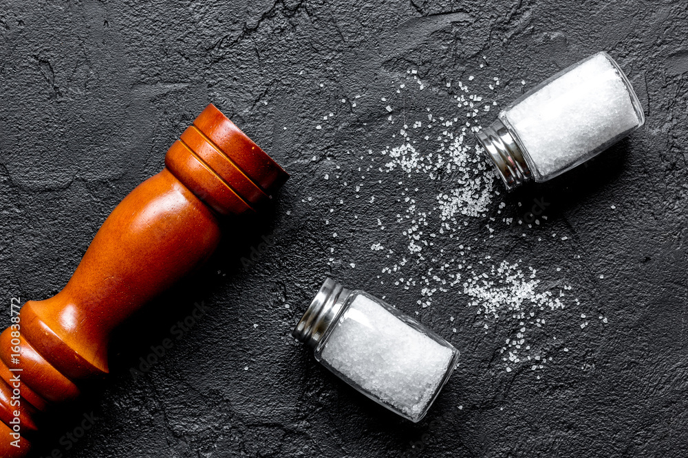 salt in glass bottle scattered on dark table background top view