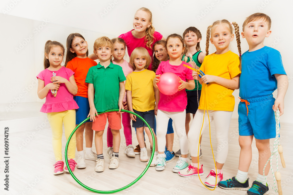 Portrait of happy sports teacher and kids at gym