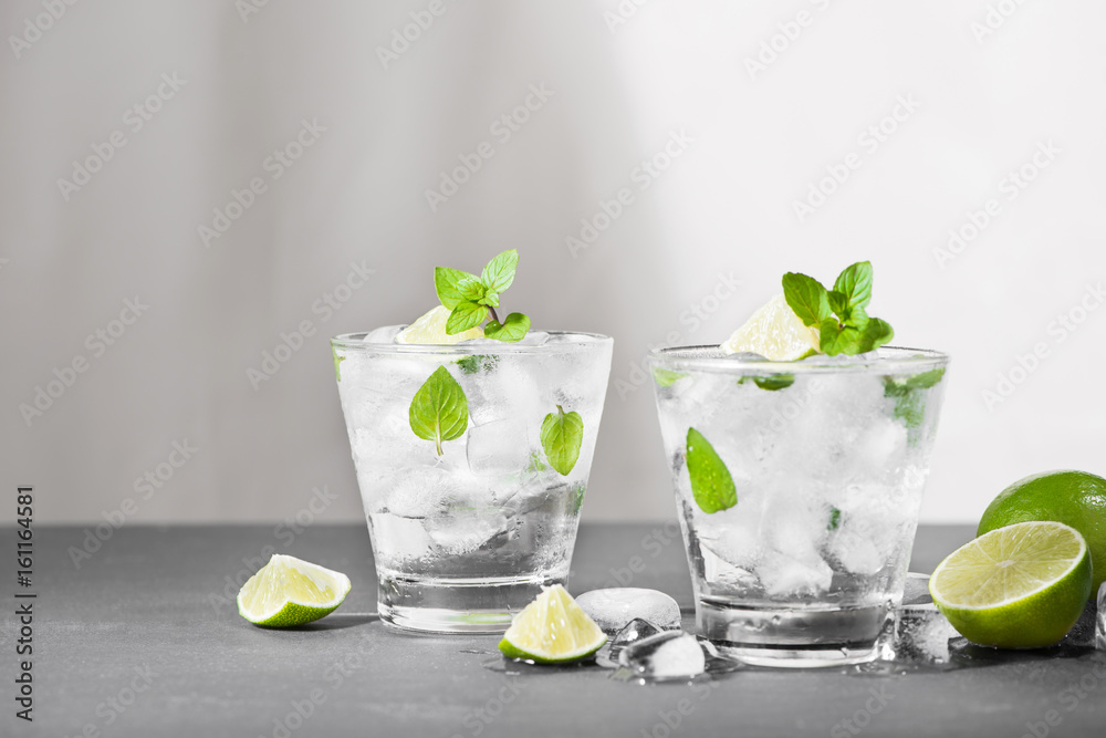 Mojito cocktail with lime and mint in glass on a grey stone background