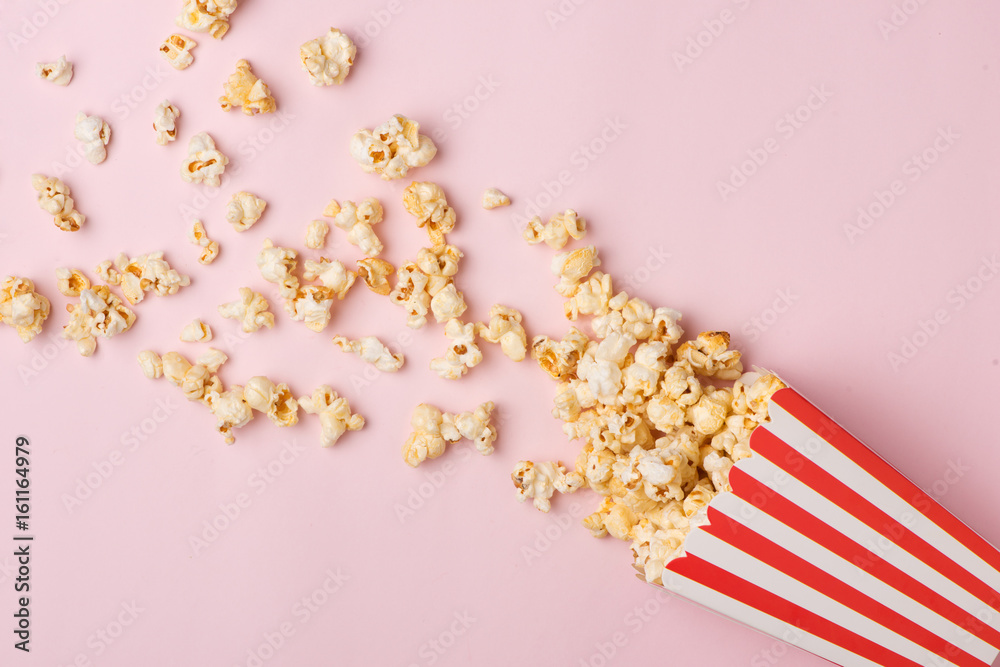 Popcorn in red and white cardboard box on the pink background.