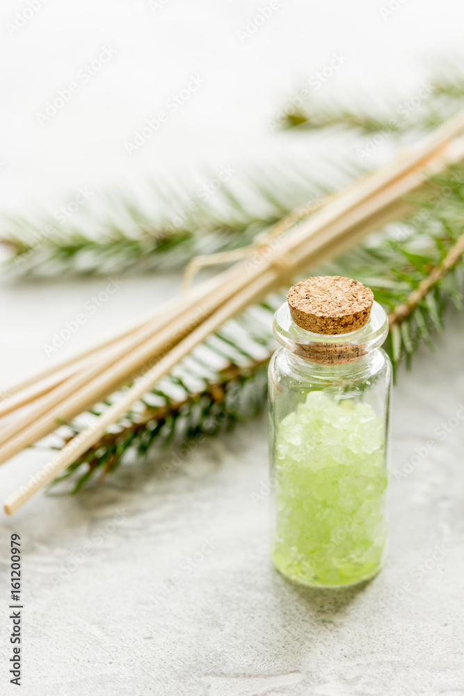 Bottles of sea salt and fir branches for aromatherapy and spa on white table background