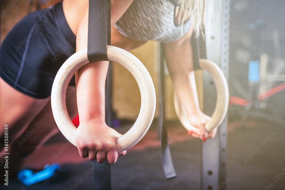 女子在crossfit健身房用体操吊环锻炼