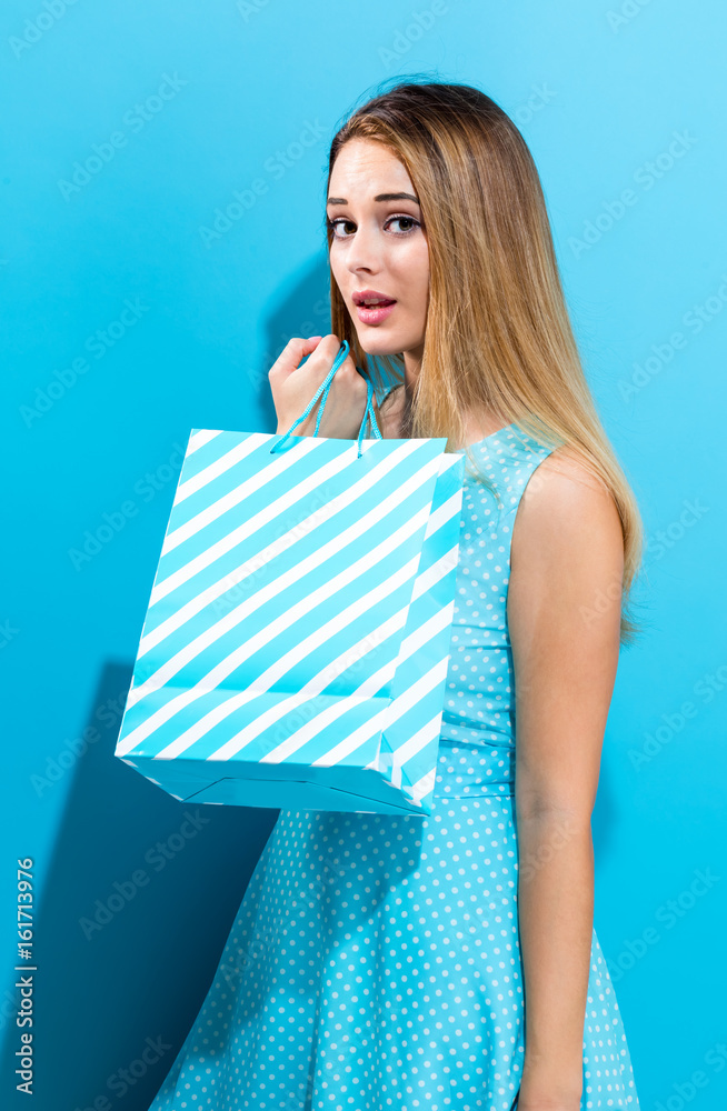 Young woman holding a shopping bag on a blue background