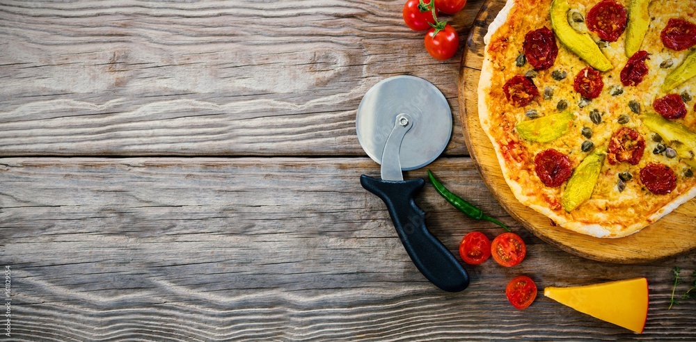 Pizza on by cutter on wooden table