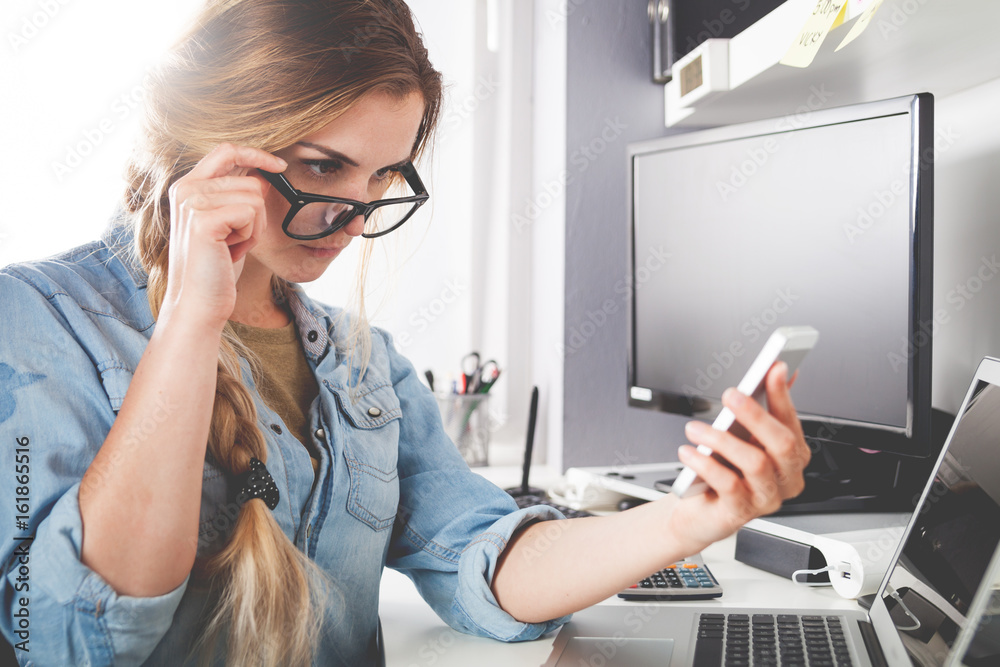 Woman working at home office while talking on phone