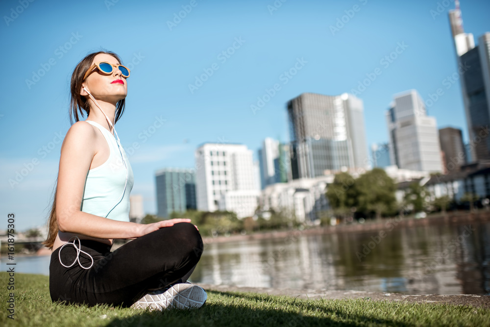 Young woman doing yoga near the river with great view on Frankfurt city