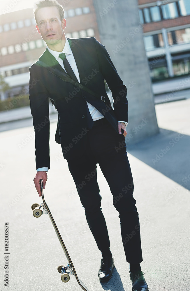 Confident handsome man wearing suit with skateboard