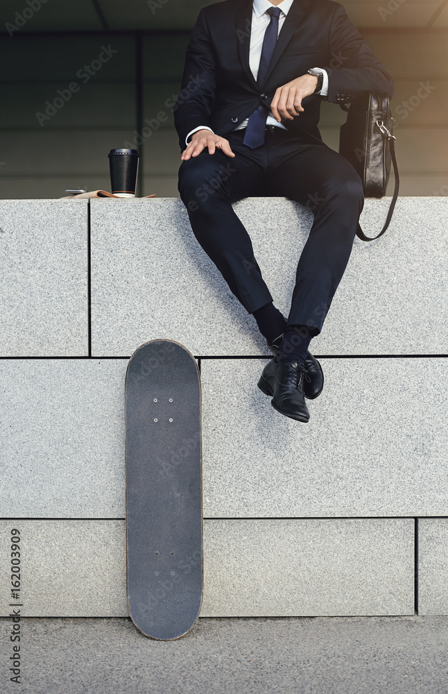 Contemporary businessman with skateboard and coffee cup