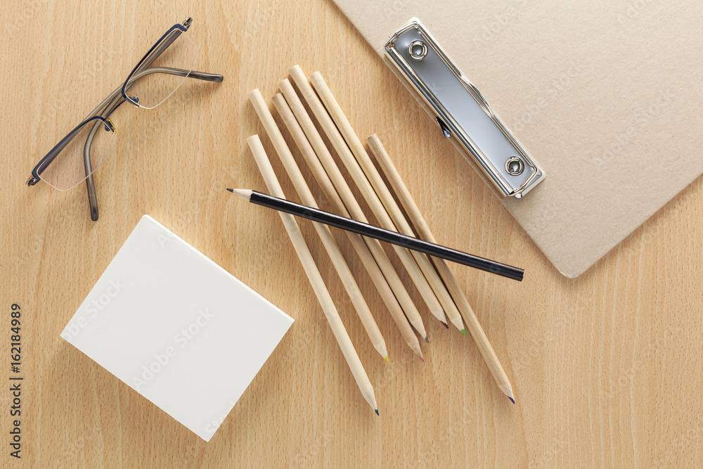 business objects of pencils,white paper note and glasses on wooden office desk.