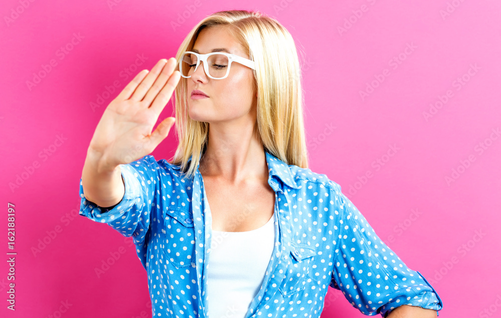 Young woman making a rejection pose on a pink background