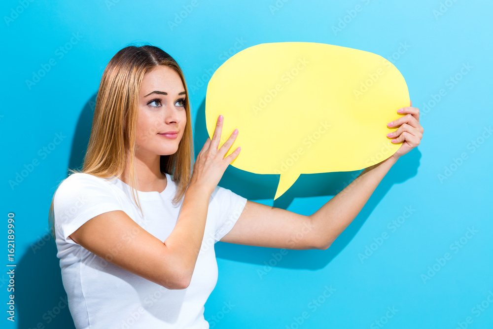 Young woman holding a speech bubble on a blue background