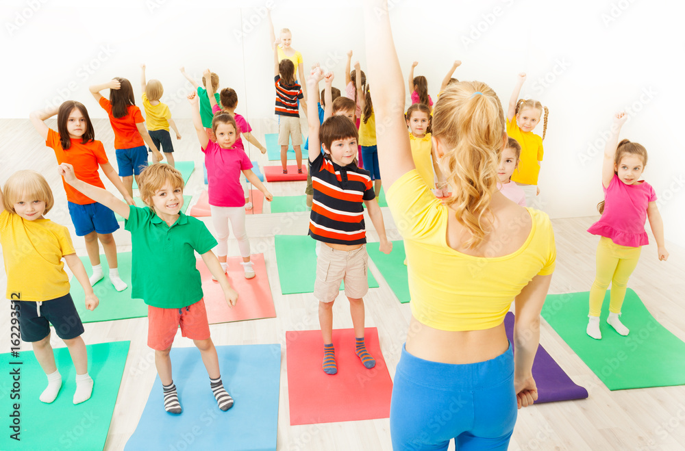 Kids doing gymnastic exercises with female coach