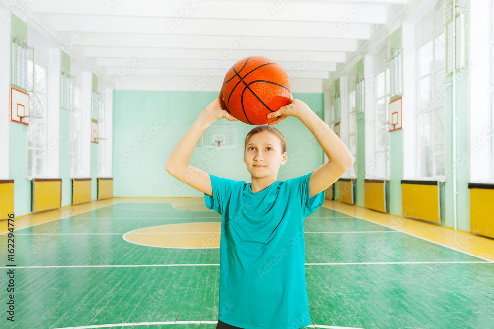 Sporty girl tossing ball in basketball rim