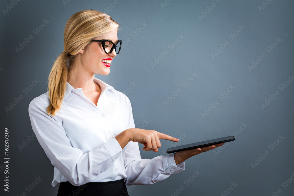 Young woman using her tablet on a gray background