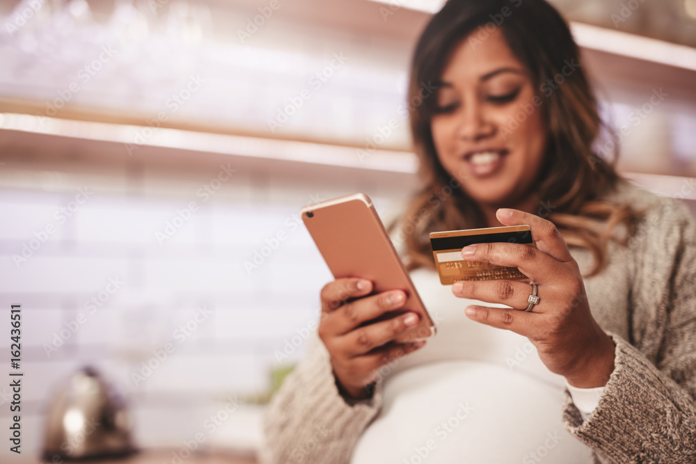 Pregnant woman shopping online with credit card and mobile phone