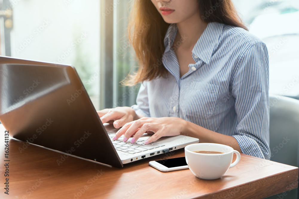 Woman using a laptop during a coffee break, hands close up