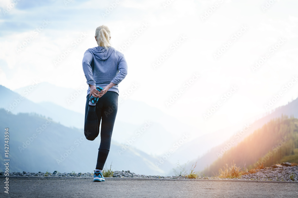 Running stretching. Athlete at the top of the mountain.