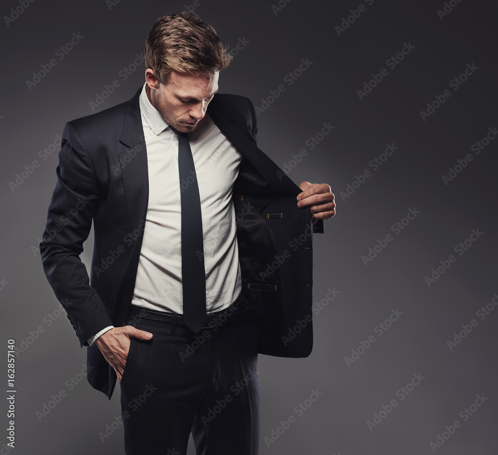 Stylish businessman in a suit standing aganst a grey background