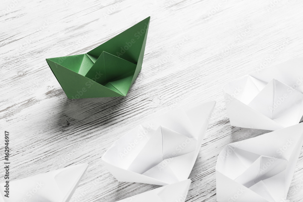 Business leadership concept with white and color paper boats on 