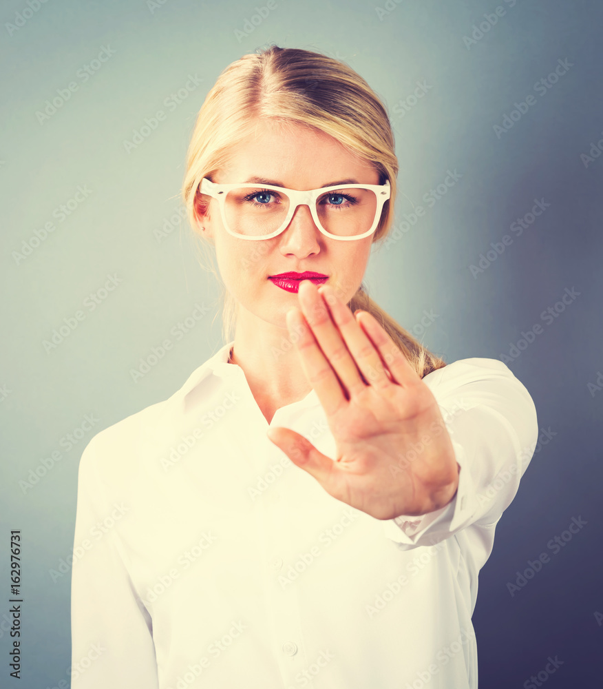 Young woman making a rejection pose on a gray background