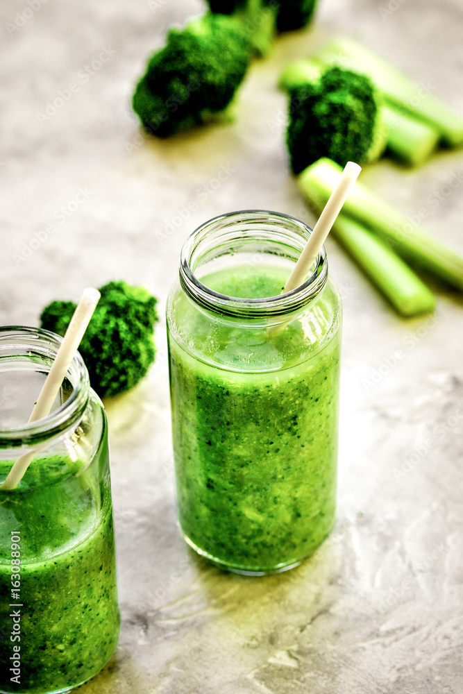 Green vegetable smoothie in glass at gray background