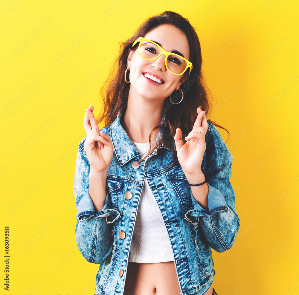 Young woman crossing her fingers and wishing for good luck