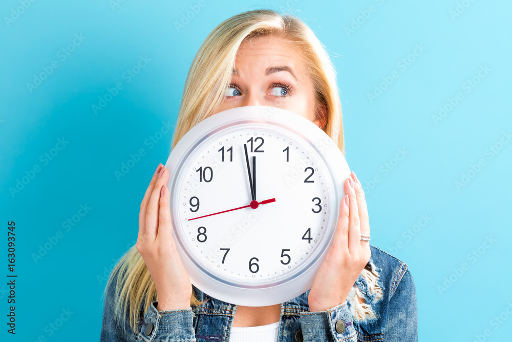 Young woman holding a clock showing nearly 12