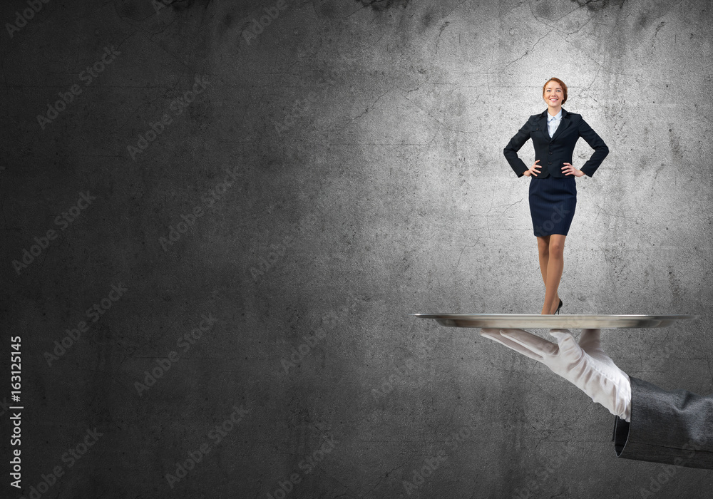 Confident elegant businesswoman presented on metal tray against concrete wall background