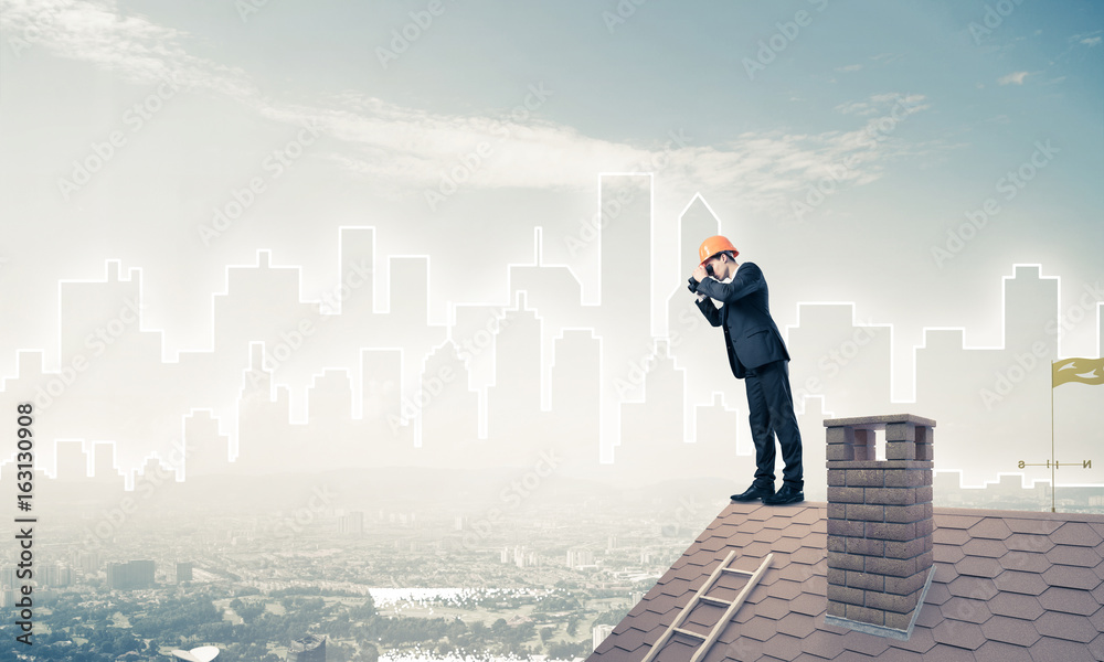 Engineer man standing on roof and looking in binoculars. Mixed m